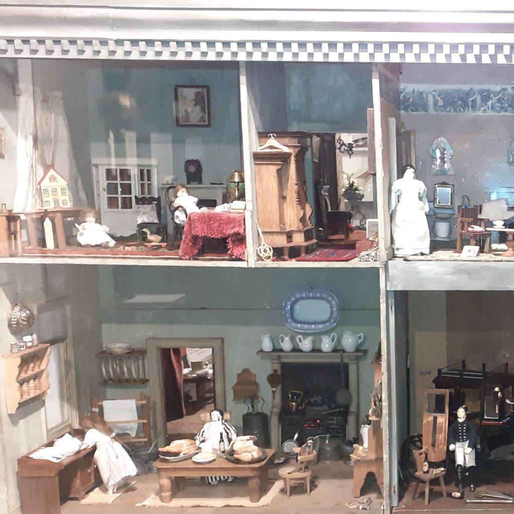 Part of a large Victorian doll's house, with furniture and figures.